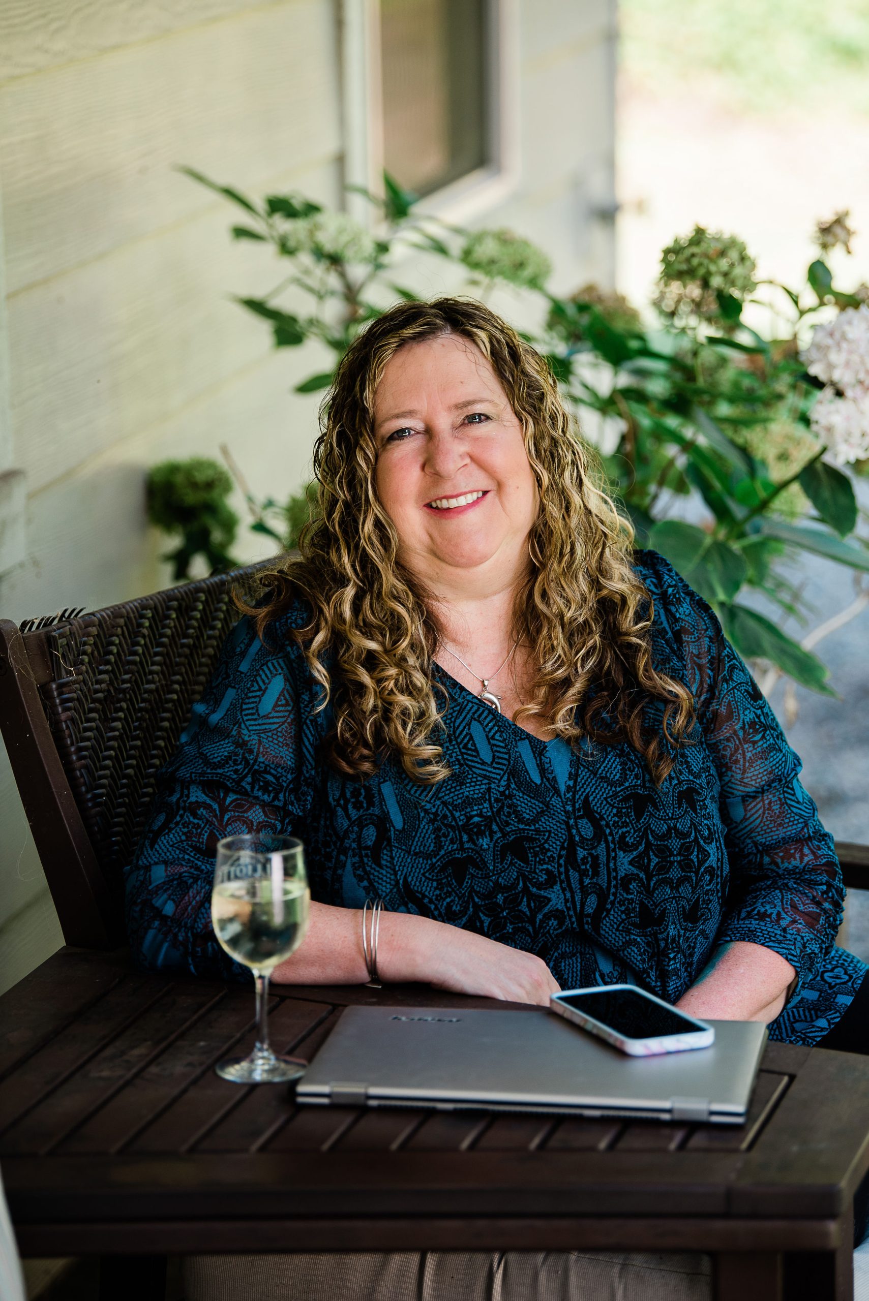 Pam Langord at her porch table in Kingston with her laptop and a glass of wine